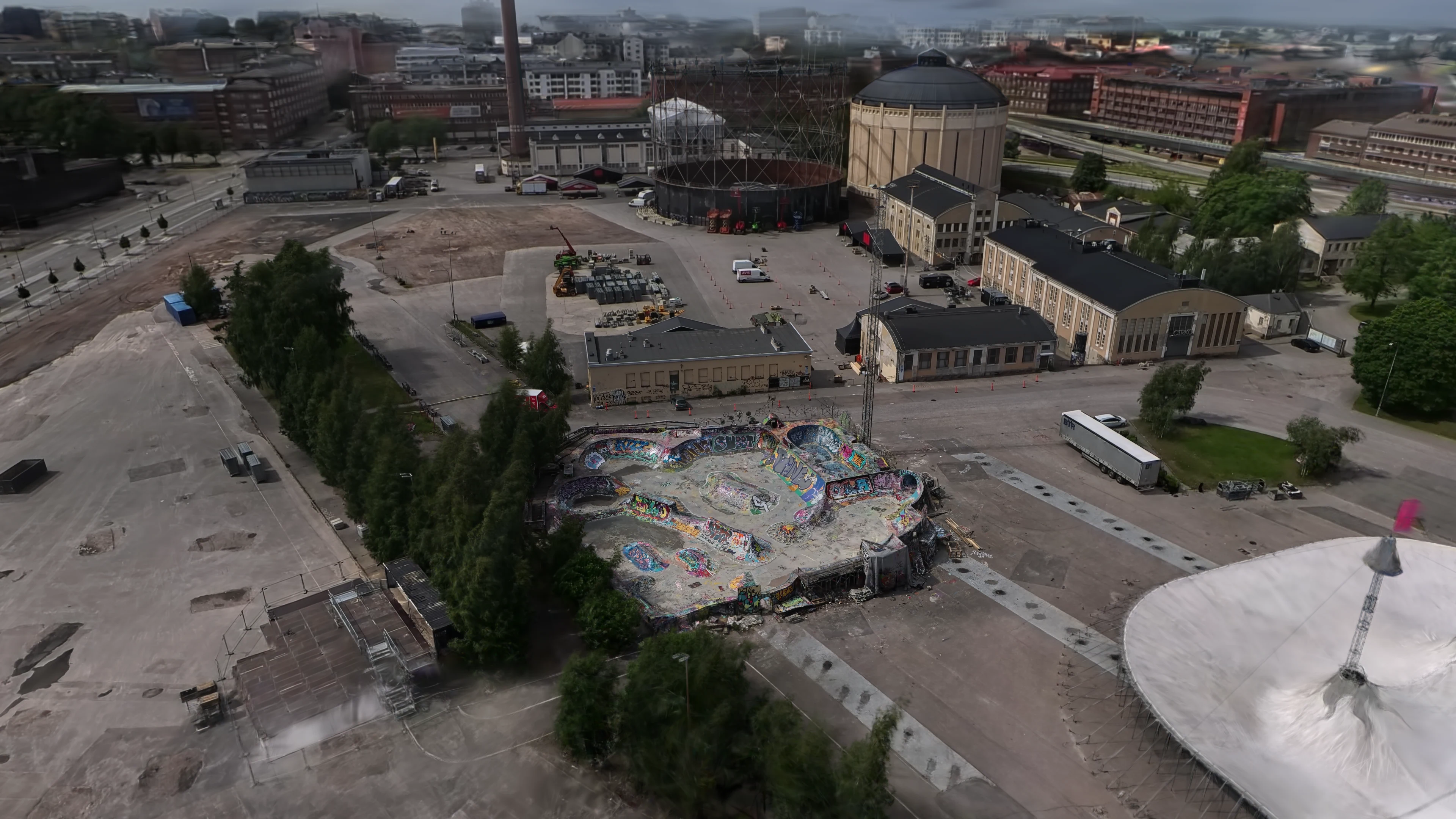 Suvilahti DIY skatepark seen from above, with the Helsinki cityscape and gas holders behind it.